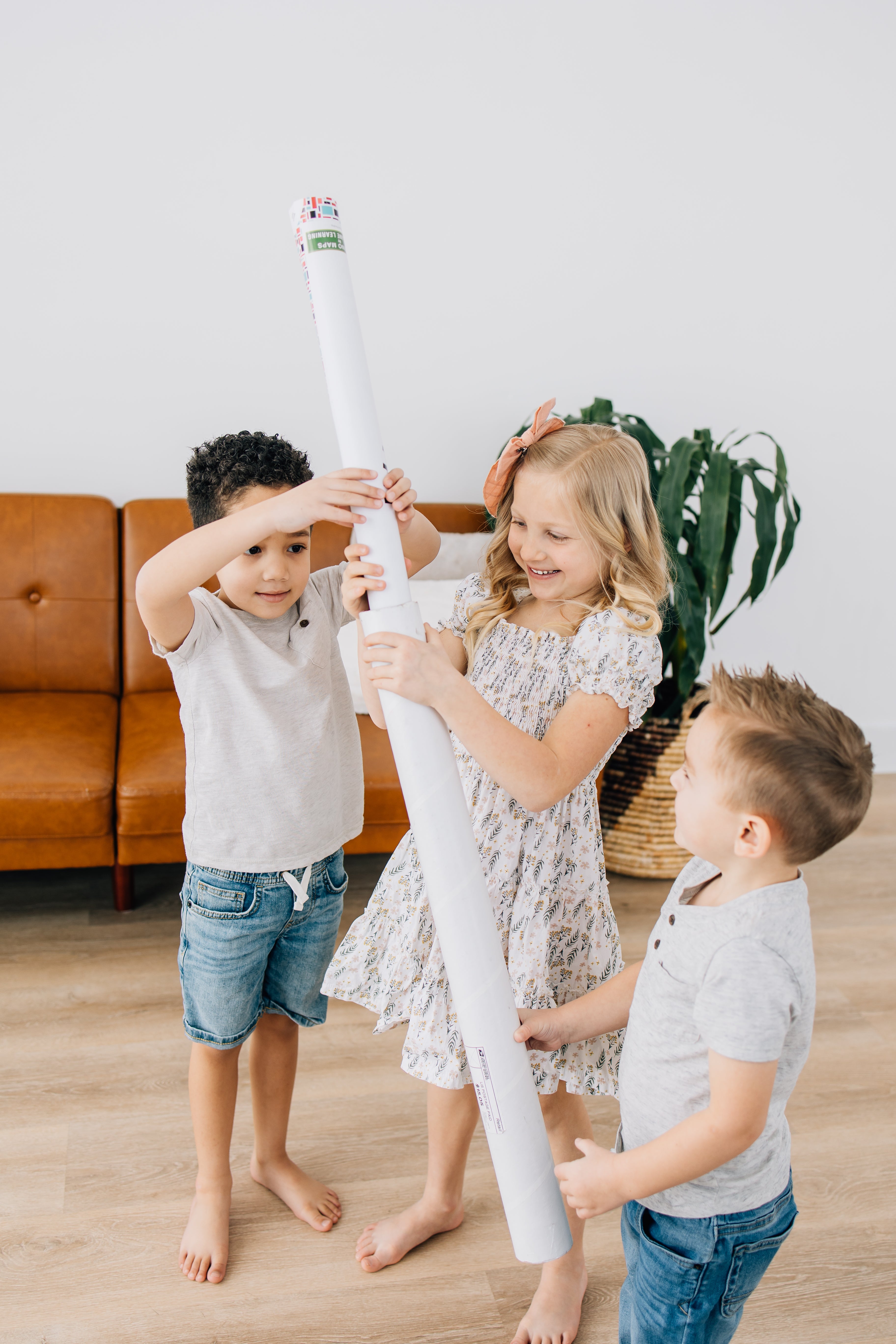 Children putting away domino map into a poster tube for storage.